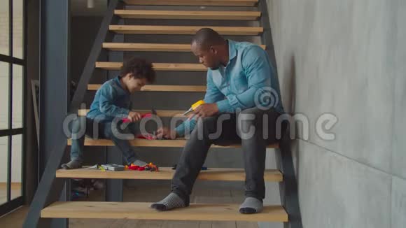 可爱的孩子和爸爸在楼梯上玩玩具工具视频的预览图