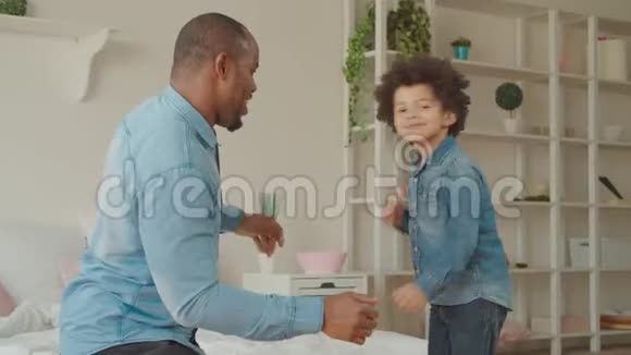快乐的黑人父亲和可爱的儿子在家跳舞视频的预览图