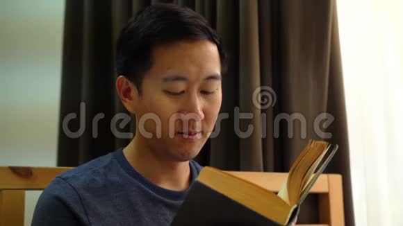 一幅30多岁的亚洲男人的肖像穿着休闲服在家里躺在床上看书娱乐和视频的预览图