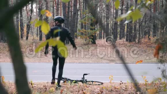 年轻的职业男性自行车运动员骑自行车服装和黑色头盔准备在秋季城市公园骑自行车训练有吸引力的视频的预览图