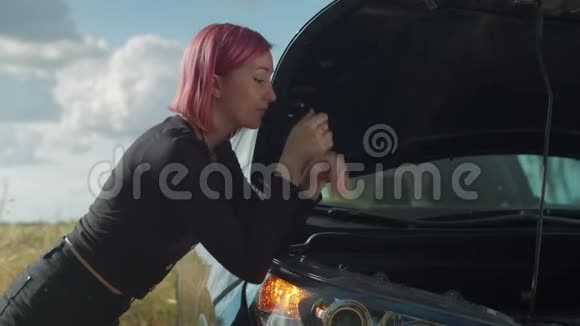 迷茫的时髦女人检查坏了的汽车引擎视频的预览图