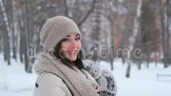 迷人的年轻女子在冬天的森林里心情愉快边看相机边旋转和微笑慢动作视频的预览图