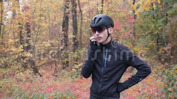 年轻的职业男性自行车运动员在秋季公园骑自行车锻炼前打电话紧张的骑自行车的家伙说视频的预览图