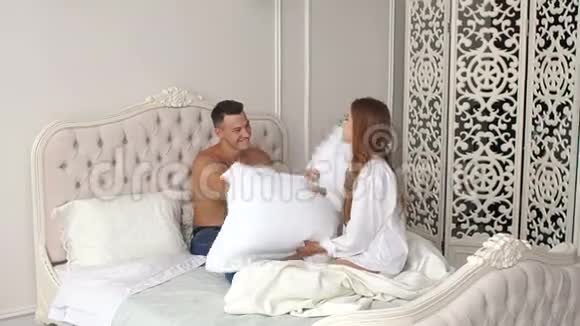 恋爱中的年轻夫妇早上在床上卧室里打枕头视频的预览图