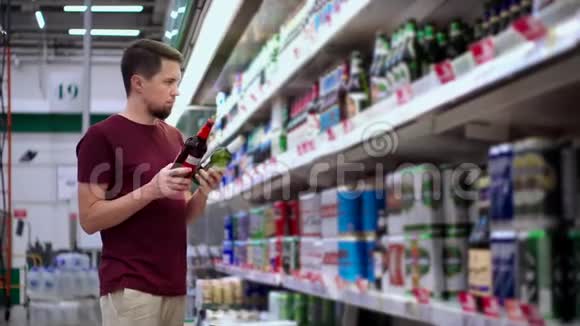 年轻人从过道超市的货架上拿啤酒瓶视频的预览图