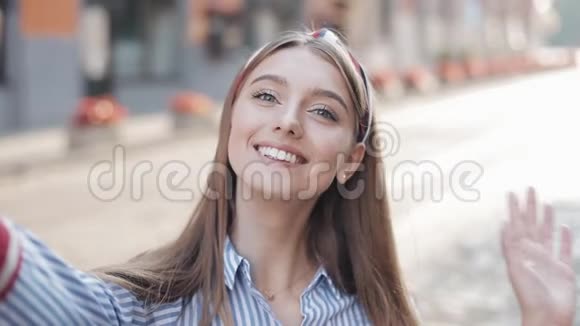 穿着带头巾的条纹衬衫的年轻迷人女孩在视频聊天中打招呼自拍视频的预览图