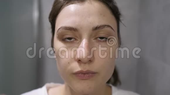 洗脸一个女孩在她的皮肤上涂上泡沫同时看着相机天然化妆品视频的预览图