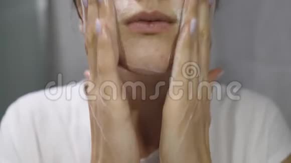 皮肤漂亮的健康女孩用白色泡沫近距离洗脸视频的预览图