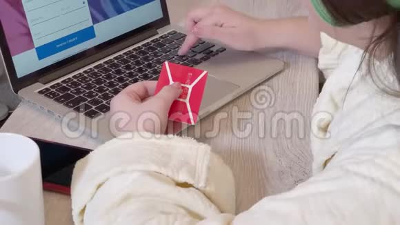 妇女使用笔记本电脑通过信用卡在线购买视频的预览图