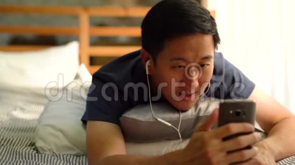 穿休闲服装的亚洲男人在家里用智能手机打电话向人们挥手的肖像视频的预览图