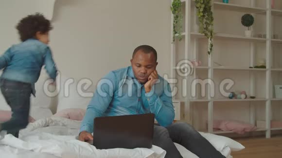 顽皮的儿子在卧室拥抱忙碌的黑人爸爸视频的预览图