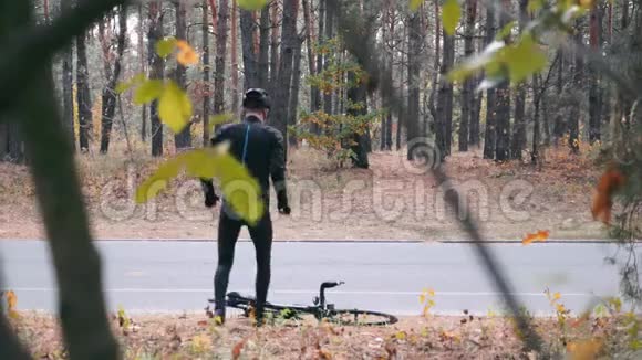 年轻的职业男性自行车运动员骑自行车服装和黑色头盔准备在秋季城市公园骑自行车训练有吸引力的视频的预览图