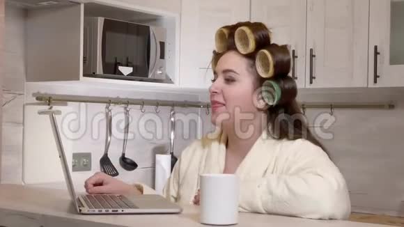 超大号的女孩穿着浴衣头上戴着卷发器通过视频通话视频的预览图