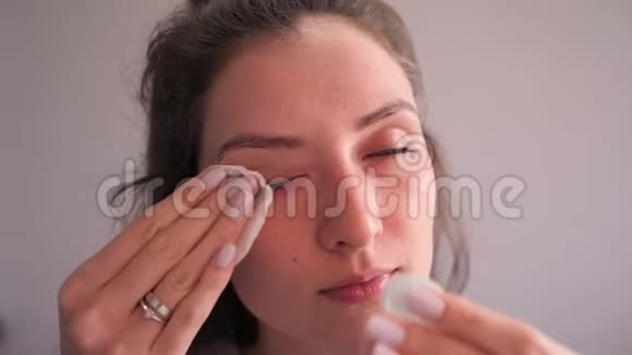 一个迷人的女孩用带有化妆水的棉盘来卸妆然后显示结果脏的棉垫视频的预览图