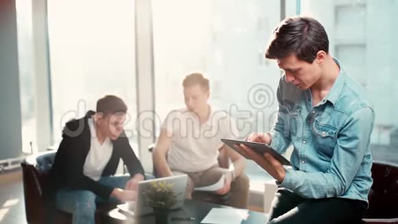 专注的年轻人在阳光明媚的办公室里使用平板电脑视频的预览图
