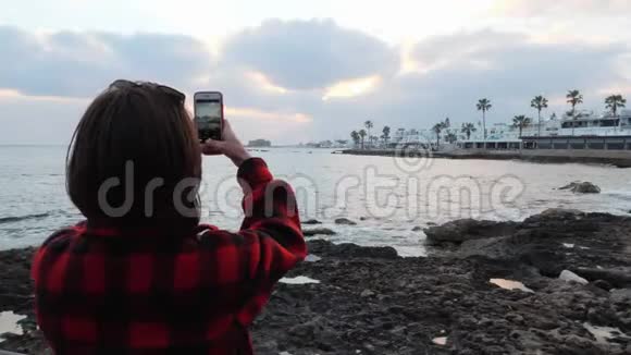 美丽的年轻黑发女子站在海滨为旅游长廊拍照有魅力的女性制作照片视频的预览图