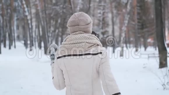 一位美丽的年轻女子回到冬天的公园然后转过身来微笑着看着相机慢动作视频的预览图