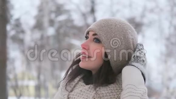 冬天公园里一个年轻的蓝眼睛女人的肖像她看着远处微笑慢动作视频的预览图