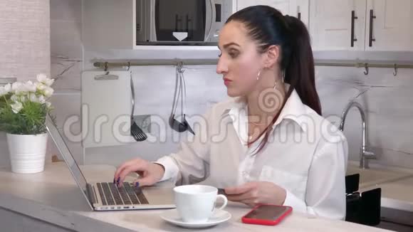 妇女使用笔记本电脑通过信用卡在线购买视频的预览图