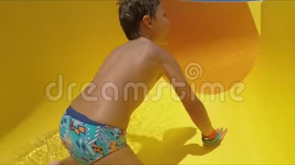 男孩骑着橙色滑梯离开公园变换位置视频的预览图