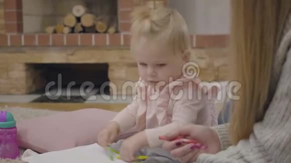 可爱的白人小女孩坐在壁炉前用彩色铅笔画画视频的预览图