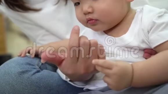 亚洲小男孩在家休息时检查和玩妈妈的手视频的预览图