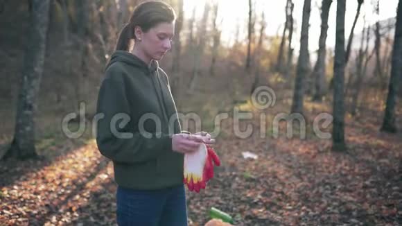 准备收集秋季森林中的垃圾和塑料垃圾女志愿者戴上手套视频的预览图