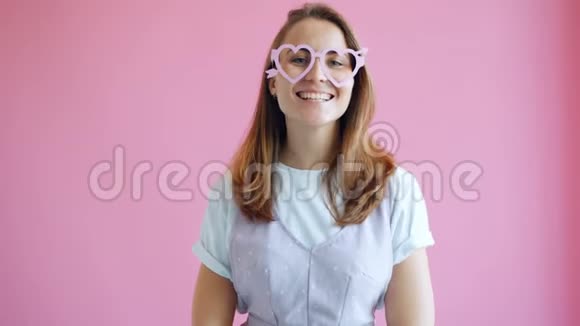 戴着搞笑心形眼镜的快乐少女的画像微笑着感到快乐视频的预览图