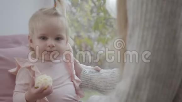 一幅可爱的白人小女孩穿着粉色上衣吃苹果的照片一个金发的婴儿和她一起四处张望视频的预览图