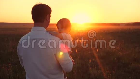 快乐的爸爸和他的小女儿在乡下散步一家人在日落时在公园休息爸爸手里拿着视频的预览图