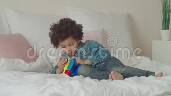 严肃可爱的小孩在床上修理玩具车视频的预览图