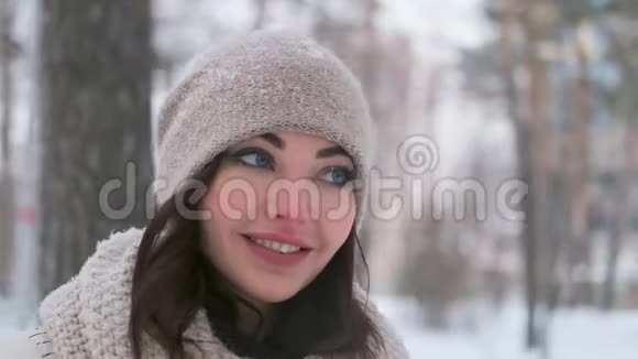 一个蓝眼睛的漂亮女孩在冬季公园里摆姿势心情很好摄像机移动视频的预览图