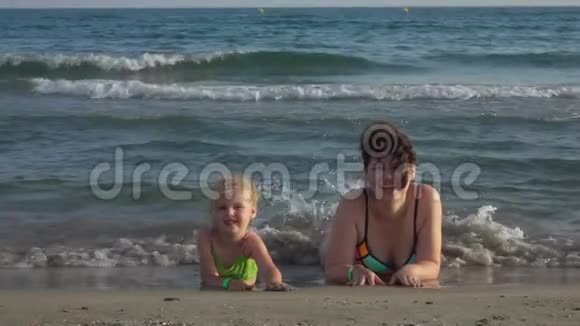 快乐的妈妈和女儿躺在海边视频的预览图