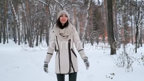 美丽的年轻女子正在一个下雪的公园里旋转仰望着欣喜着视频的预览图