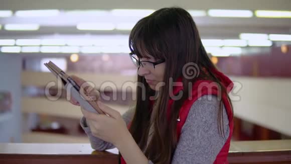 年轻的黑发女人用平板电脑在商场里连续工作视频的预览图