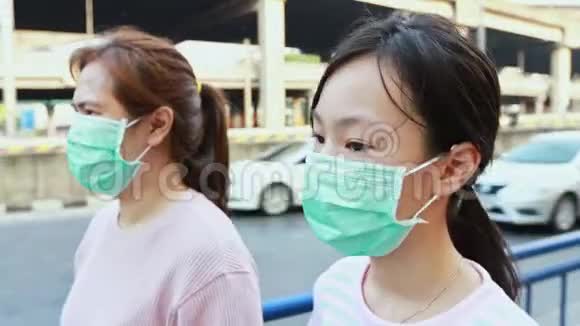 戴着卫生口罩的亚洲母女在户外行走对灰尘污染空气污染过敏PM25医疗保健病毒视频的预览图