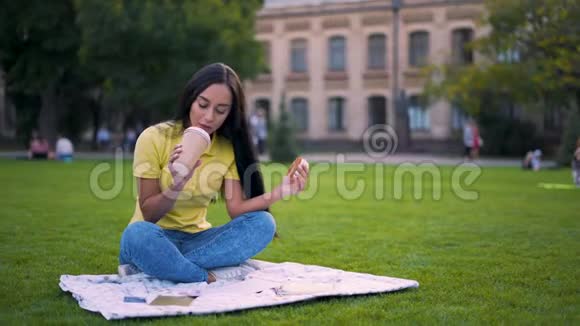 喝杯咖啡长发拉丁女孩坐在公园里吃午饭4K视频的预览图