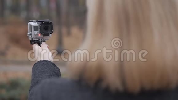 一位女性博主在秋天的公园里散步时拍摄了一部溪流动作相机从后面看到的视频的预览图