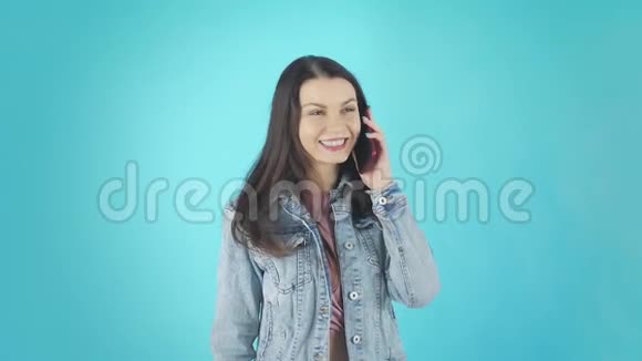 一个穿着牛仔夹克的年轻微笑的女人正在打电话笑视频的预览图