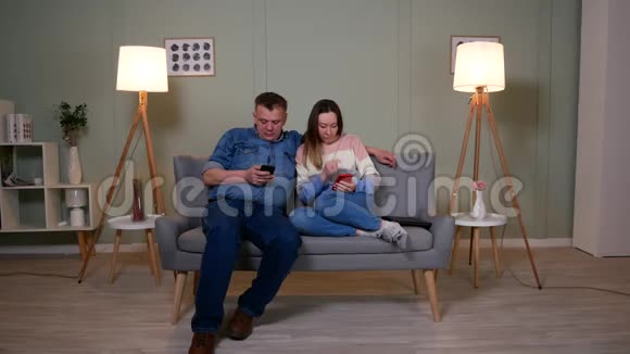 两个人坐在沙发上玩手机视频的预览图