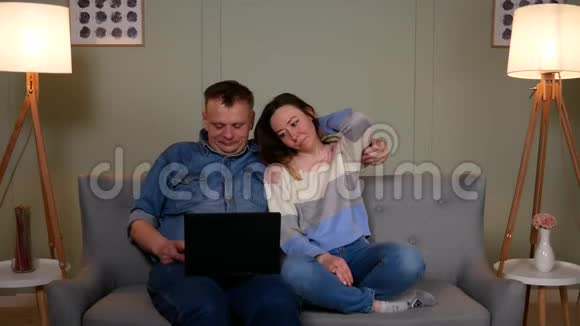 两个人坐在沙发上看着笔记本电脑上的东西视频的预览图