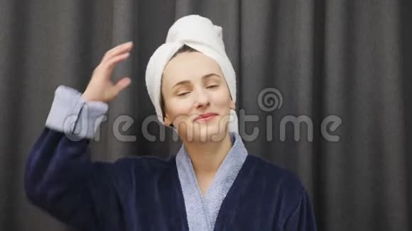 女人从头上摘下毛巾摸湿头发年轻的女性穿着蓝色浴袍洗澡后头发湿透健康与美容视频的预览图