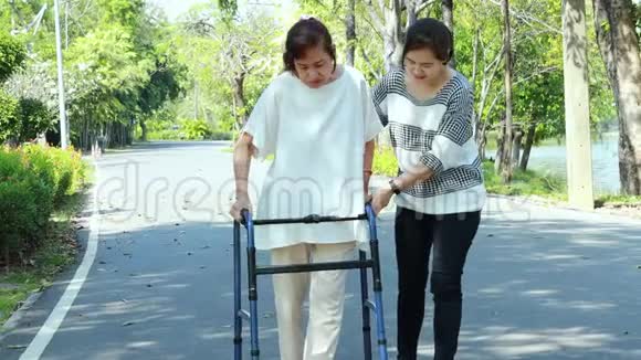 亚洲老年妇女在膝关节手术后的康复过程中使用助行器年轻的护理人员协助让成熟的老年人安心视频的预览图