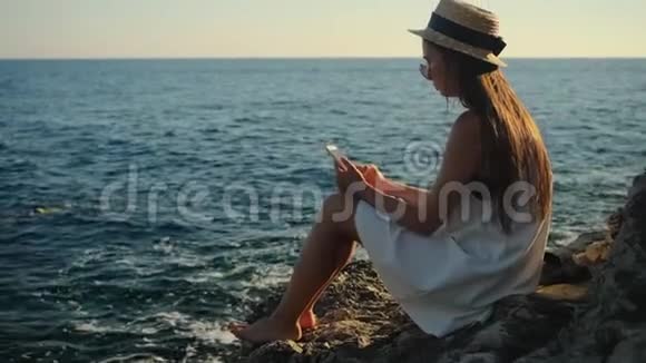 今年夏天坐在海上悬崖上的女人正在打字视频的预览图