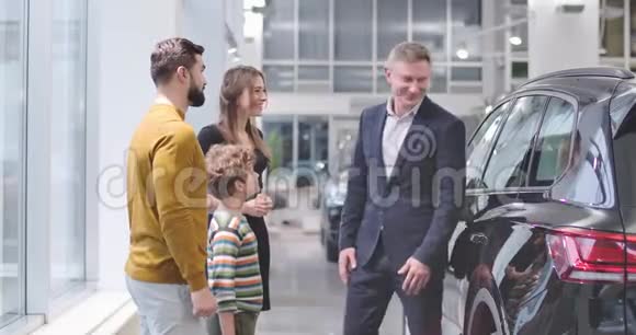 成功的高加索商人与成年男性顾客和他的儿子握手年轻漂亮的女人站在旁边视频的预览图
