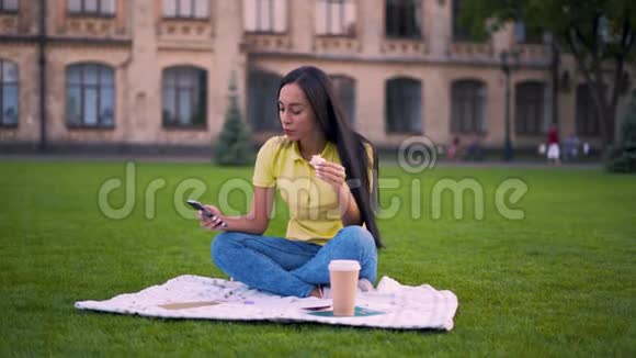 野餐的小女孩女孩滚动手机吃三明治4K视频的预览图