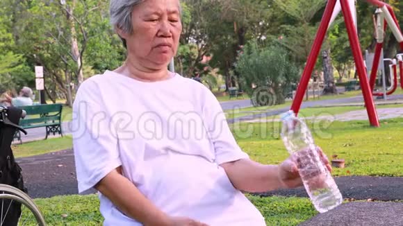 亚洲老年妇女有原发性震颤老年人握着一瓶水喝时有握手症状老年人有发抖症状视频的预览图
