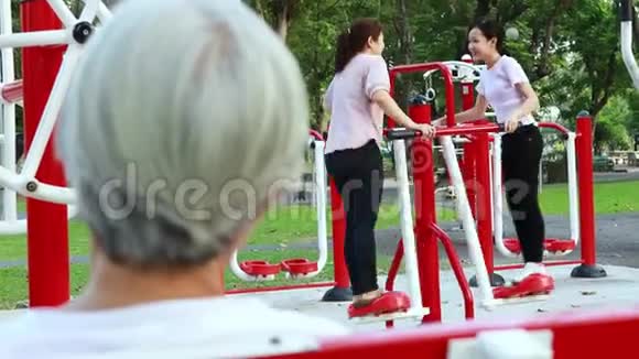 快乐的亚洲女人母亲和女儿享受着在公共公园里用健身机锻炼身体和健康的孩子玩耍视频的预览图