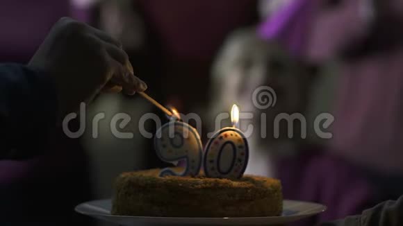 男性手在蛋糕上点蜡烛90岁妈妈生日家庭护理视频的预览图