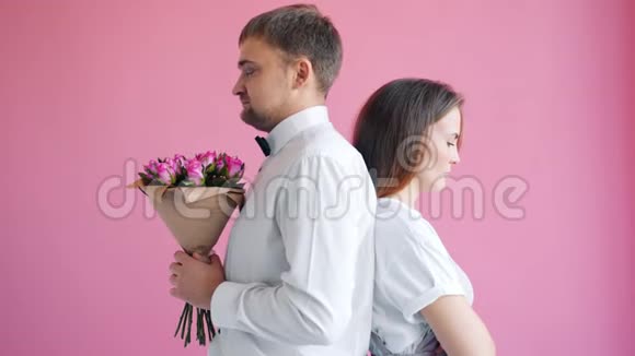 悲伤的一对夫妇背靠背站着男人送花给女孩让她快乐视频的预览图